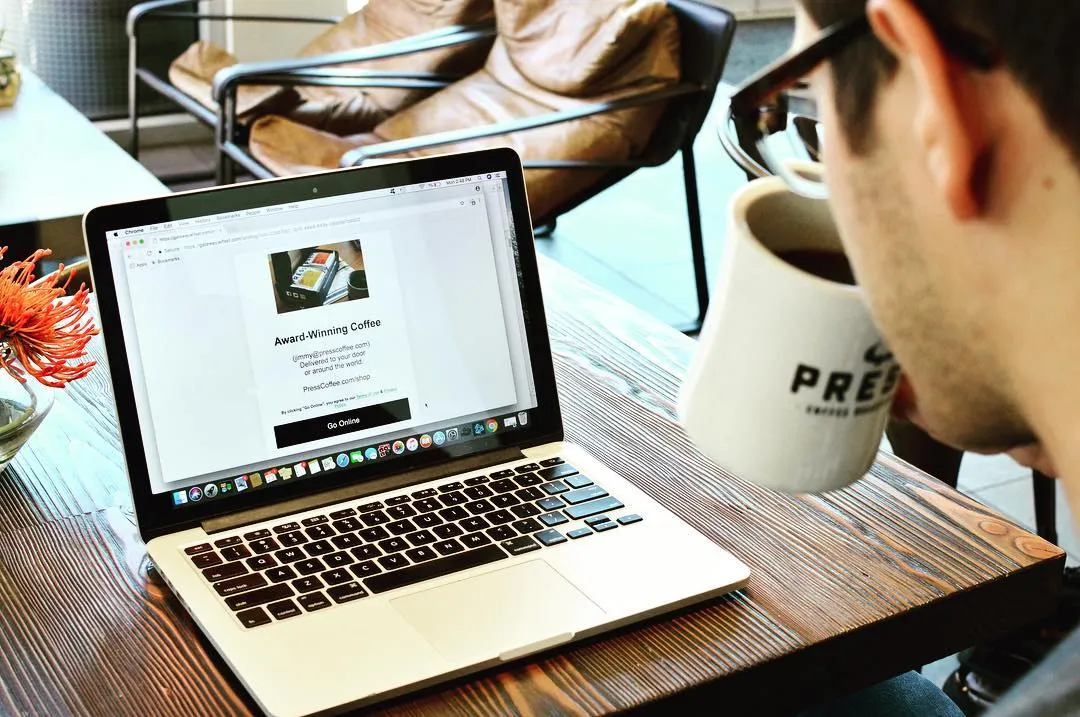 Someone sipping coffee next to a laptop showing a Zenreach email campaign for an award-winning coffee shop